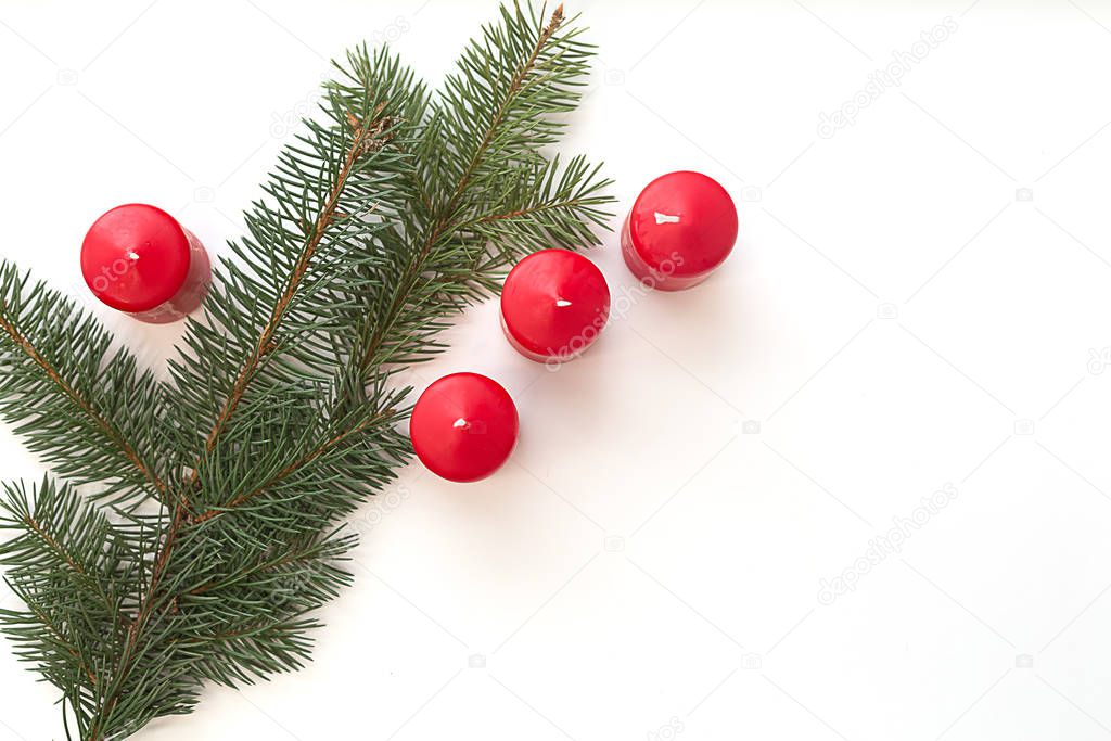 Candles and Christmas green pine branch on a light background.