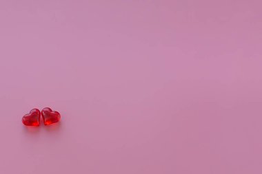 Pembe arka planda iki kırmızı cam kalp. Kompozisyon Valentine