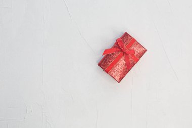 Açık desenli arka planda bir hediye olan kırmızı kutu.