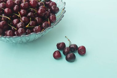 Hafif arka planda taze kokulu kirazlı cam bir tabak. Seçici odaklanma. Model ve projeniz için minimalist konsept. 