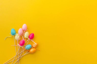 Paskalya kompozisyonu. Pembe parlak sarı arka planda çok renkli yumurtalar. Seçici odaklanma. Model ve projenin konsepti. Düzen, düz yatış, kopyalama alanı, üst görünüm.