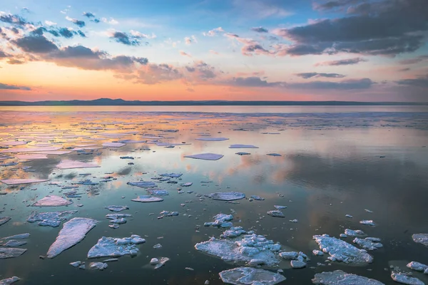 夕日は 氷の塊が浮かぶ海の表面に反映されている様々なパステルカラーで空を描きました — ストック写真