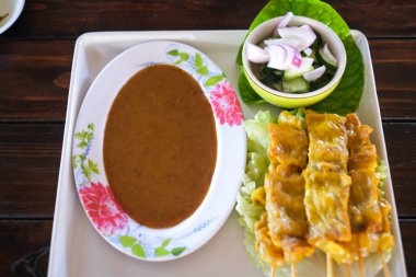 Fıstık soslu ve turşulu domuz eti, salatalık dilimleri ve sirkeli soğan..