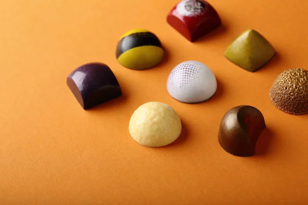 Assortimento caramelle al cioccolato su sfondo arancione — Foto Stock