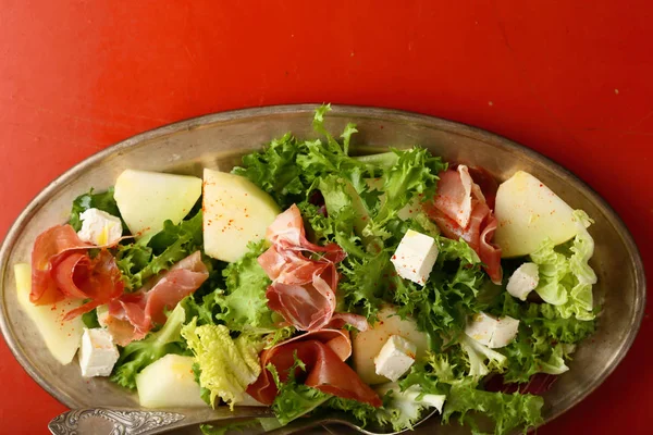 Salad with prosciutto and melon slice on dish — Stock Photo, Image