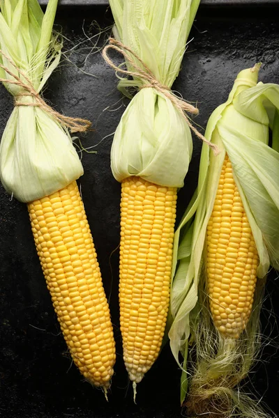 Mazorca de maíz fresco crudo sobre fondo negro — Foto de Stock