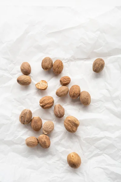 Aromatic nutmegs spice on white paper — Stock Photo, Image