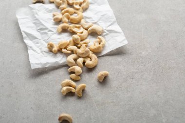 Beton arka planda beyaz kağıt üzerinde kaju fıstığı