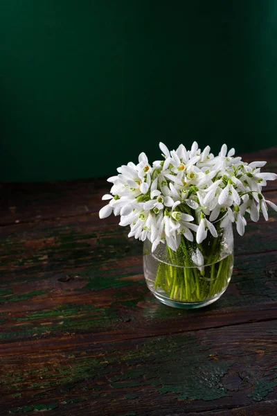 Jarní květiny ve skleněné váze na venkovském zeleném pozadí — Stock fotografie