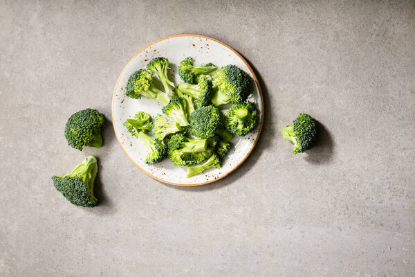 Fresh raw broccoli on plate light surface, healthy food concepts