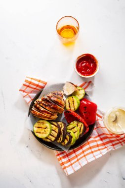 Kızarmış et ve sebzeler tabakta taş masada.