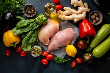 Bir grup sağlıklı sebze ve çiğ et. Karanlık yüzeye kurulmuş yiyecek.