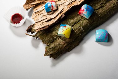 Modern chocolate candy in wooden bark, overhead view clipart