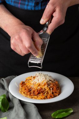 Bolonez makarnası. Erkekler Eller spagettide peynir rendeliyor 