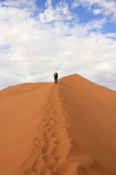 Turista escalando una duna en el desierto de Sossusvlei, Namibia — Foto de Stock