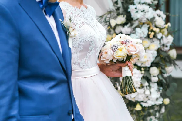 Bruid en bruidegom bedrijf een bruiloft boeket in handen — Stockfoto