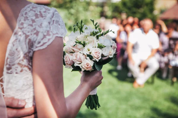 Невеста держит свадебный букет перед гостями — стоковое фото