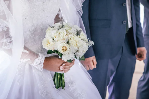 Braut und Bräutigam halten einen Brautstrauß in den Händen — Stockfoto