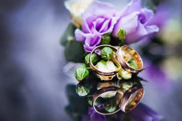 Wedding rings on a violet flower — Stock Photo, Image