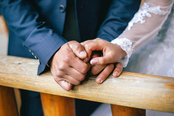 Brudgummen håller brudens hand — Stockfoto