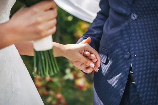 De bruidegom houdt de hand van de bruid vast — Stockfoto