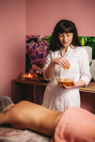 Woman massage therapist, with honey massage on the back