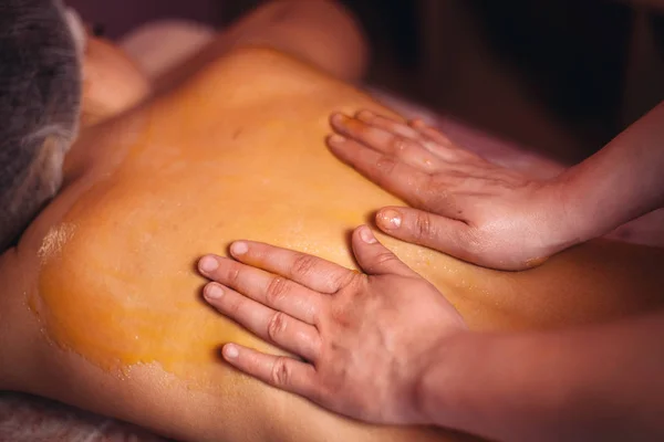 Vrouw massagetherapeut, met honing massage aan de achterzijde — Stockfoto