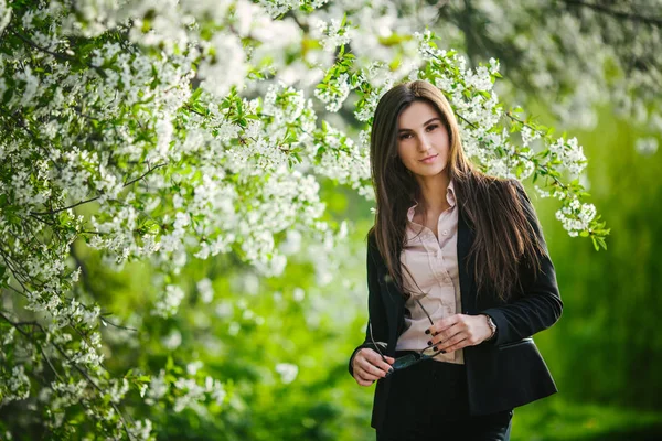 Mooi meisje in de buurt van bloeiende bomen — Stockfoto