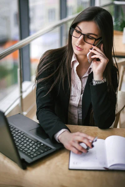 Mujer de negocios sentada en una oficina blanca y recibiendo llamadas en la mesa — Foto de Stock