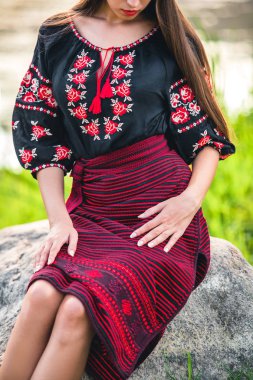 bir şerit ve desenleri ile siyah bir bluz işlemeli bir etekle kız oturuyor