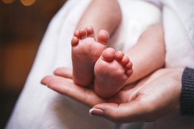 Anne çocuğun ayak kendi elleriyle tutar.