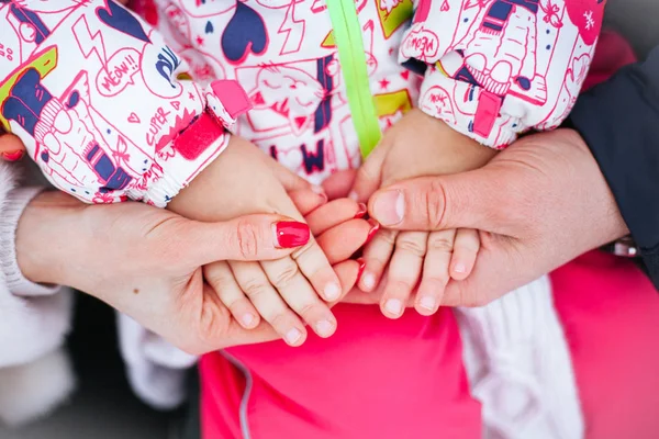 parents hold the child\'s hands with their own hands