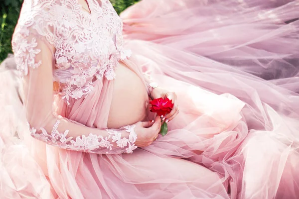 Schwangere Sitzt Rosa Kleid Mit Spitze Und Hält Eine Blume — Stockfoto