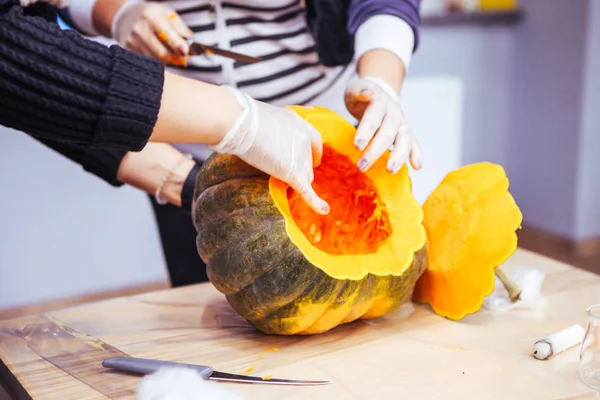 people prepare a pumpkin for the holiday of halloween