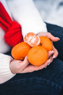 kız beyaz kazak ve kırmızı eşarp mandalina onun elinde tutan kışın