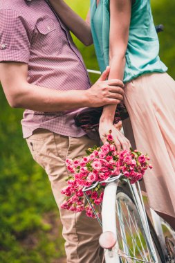 Gönül tribünde bir bisiklet ile bir yazıt ve bir sepet çiçek yakınındaki yaz parkta bir çift