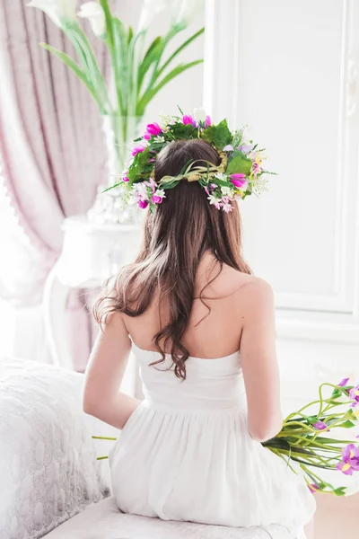 Nevěsta Zády Sedí Bílých Šatech Posteli Květinový Věnec Hlavu Místnosti — Stock fotografie