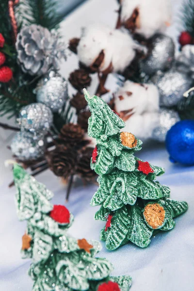 souvenirs from ceramics in the form of Christmas trees stand on a background of a Christmas branch