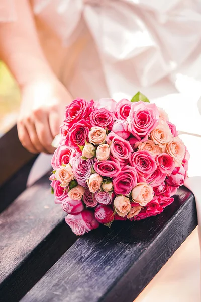 Noiva Coloca Buquê Brilhante Rosas Tons Vermelhos Banco Parque — Fotografia de Stock