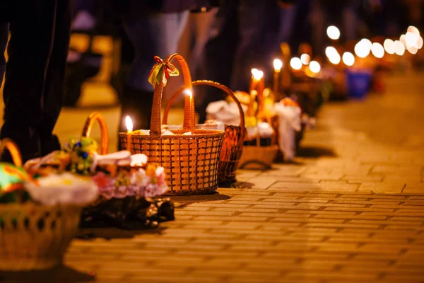 教区居民在复活节蛋糕上点燃的蜡烛在篮子里照亮在清晨在教堂附近的街道照明 — 图库照片