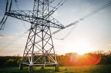 bir yüksek voltajlı güç alanını şehir dışında gün batımında çizgidir