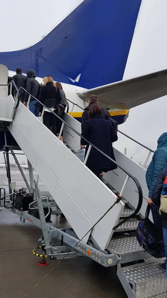 Passengers climb the ramp to the plane