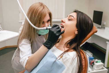 Kız dişçide oturuyor ve dişlerini tedavi ediyor.