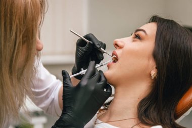 Dişçi hastaya anestezi iğnesi yaptı.