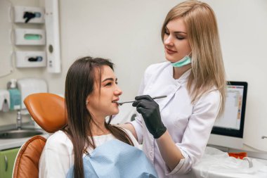 Dişçi kız dişlerine karbon kağıdı yapıştırıyor.