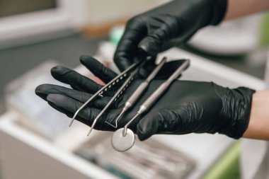 Diş doktoru elinde eldivenli bir alet tutuyor.