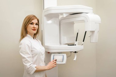 dentist girl stands near the apartment panoramic roentgen of teeth and looks at the camera