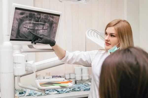 girl dentist shows an roentgen to the patient in the office for bad teeth
