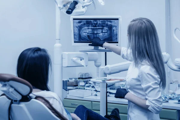 Girl dentist shows on roentgen to patient — Stock Photo, Image