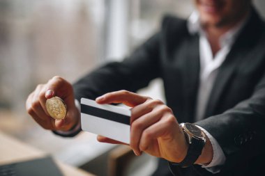 Adamın elinde Bitcoin ve kredi kartı var.
